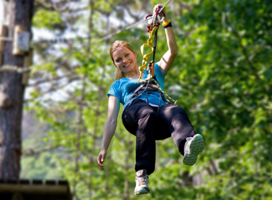 A girl glides along a zip line, enjoying the challenge at the Postojnsko Adventure Park, set among the trees of a peaceful woodland on the edge of town.