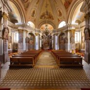 The magnificent interior of the Church of St Stephen in Postojna features vaulted ceilings adorned with decorative sacred frescoes. A grand altar forms the focal point of the church, flanked by beautifully crafted wooden confessionals.