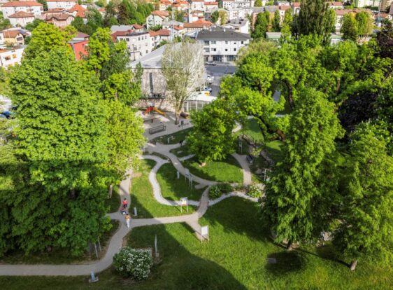 The photograph shows the town park, where winding paths meander through the Faces of Our History exhibition. Surrounded by mature trees and expansive green spaces, the park also offers a welcoming setting for children to play and visitors to relax.