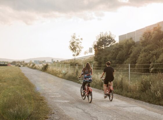 A girl and a boy cycling along a flat gravel road.