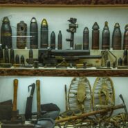 The photograph shows tools, weapons, and military equipment from the First World War on display as part of the collection at the Pri Stara dama Museum in Predjama.