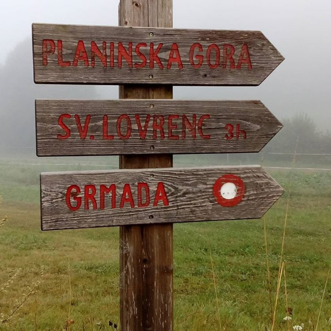 Lesen smerokaz z napisi Planinska gora, Sv. Lovrenc in Grmada na travniku v megli.