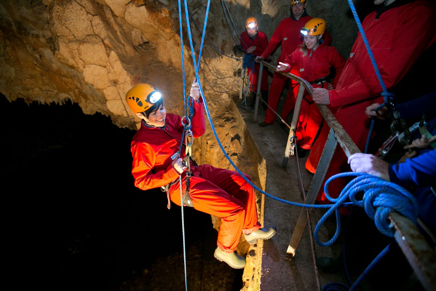 Cave trekking in Postojna Cave. A group of adventure seekers descends into the underground world with the guidance of experienced cavers and the support of ropes.