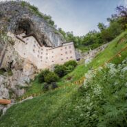 Predjamski grad od spodaj navzgor. Izžareva veličino več kot 80 metrov visoke stene, v katero je grad vpet. Pod njim pa se skriva vhod v podzemni svet Jame pod Gradom.