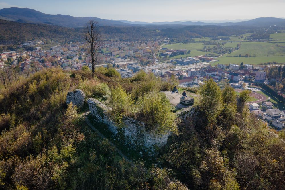 Ostanki gradu Adelsberg oz. Postojnskega gradu, preraščeni z grmovjem in zelenjem. Na vrhu pa zgolj lipa še kljubuje času po žledu in nas opominja na trdnost in vztrajnost, ki jo Postojnčani nosimo v sebi.